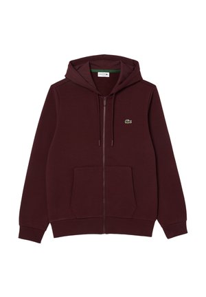 Sudadera con cremallera de color marrón hecho de tela suave, que cuenta con un bolsillo tipo canguro en la parte delantera, una capucha con cordón y un logotipo bordado en verde en el pecho.