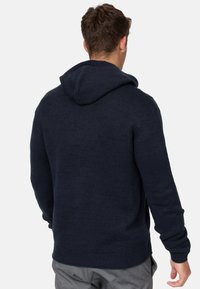 Navy blue knitted hoodie with a textured finish, featuring a spacious hood and ribbed cuffs. Clean design with no visible logos.