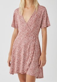 Vestido envolvente con estampado floral rojo y mangas cortas. Presenta un escote en V profundo, cintura ajustada y un dobladillo con volantes. Tejido ligero.