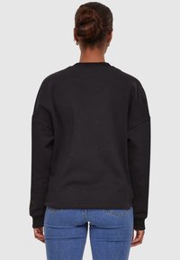 Black sweatshirt with a round neckline, oversized fit, and dropped shoulders. Material appears soft with a smooth finish. Simple design.