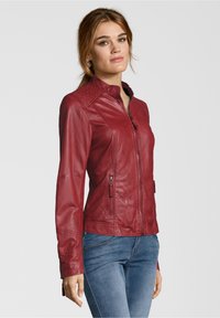 Rote Lederjacke mit enganliegendem Design, Reißverschluss und zwei Seitentaschen. Mit hohem Kragen und strukturierten Schulterakzenten.