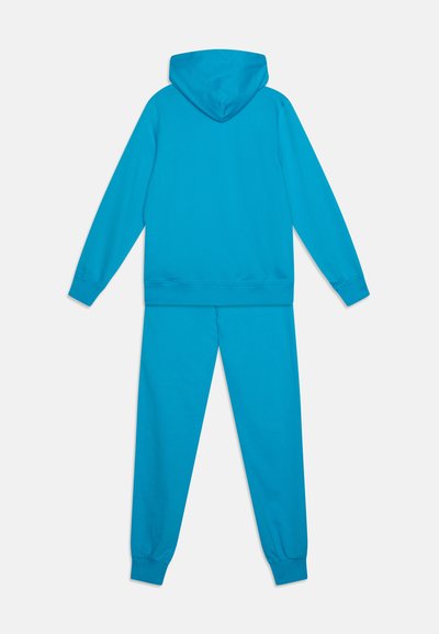 Conjunto de sudadera con capucha y pantalones en un brillante color turquesa. Tejido suave, puños acanalados, corte relajado y sin logotipos ni patrones visibles.