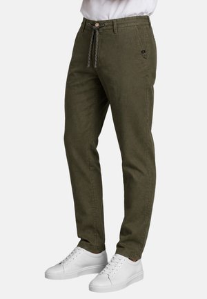 Dark olive green casual pants with drawstring waist and side pockets, worn with white low-top sneakers and a tucked white shirt.