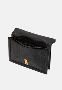 Czarna skórzana kopertówka o fakturze krokodyla, ze złotymi detalami i zamykanym wnętrzem. Prostokątny kształt z klapką.