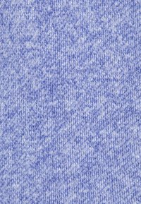 Ljusblått stickat tyg med en mjuk textur, med ett subtilt mönster av invävda fibrer och varierande nyanser av blått över hela ytan.