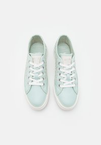 Světlomodré tenisky s bílými tkaničkami, na bocích se strukturovaným panelem, polstrovaným límcem a gumovou podrážkou. Značková etiketa je viditelná uvnitř.