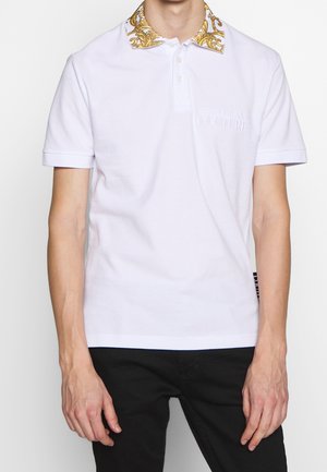 Camisa polo de manga corta blanca con un collar dorado estampado. Presenta un sutil logo en el pecho. Fabricada con material de algodón transpirable.