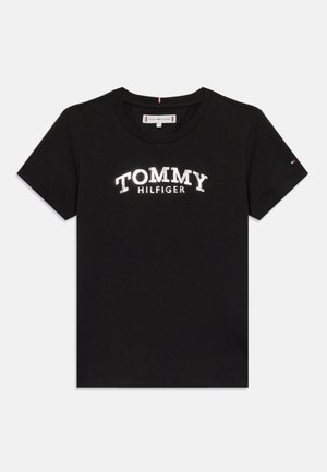 Camiseta negra de manga corta con el texto "TOMMY HILFIGER" en blanco en el pecho y un pequeño logo de la bandera de Tommy Hilfiger en la manga izquierda.