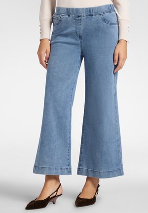 Pantalones de mezclilla de pierna ancha en un azul claro con cinturilla elástica, dos bolsillos frontales y un acabado de dobladillo limpio. La tela muestra una textura suave.