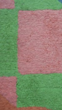 Gros plan flou d'une surface texturée avec de grands blocs de couleur rectangulaires rose et vert.