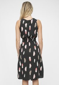 Czarna sukienka z dopasowaną górą i marszczonym paskiem w talii, zdobiona wzorem piór w odcieniach różu i beżu, z zwiewną spódnicą.