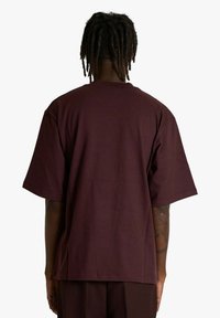 T-shirt bordeaux a maniche corte con vestibilità comoda e scollo rotondo, realizzata in cotone morbido. Retro semplice senza marchi visibili o motivi.