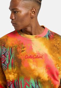 Multikleurige sweatshirt met een mix van oranje, roze en groene tinten, voorzien van een textuurpatroon en geborduurd "Calo Colucci" logo.