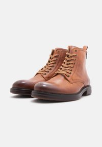 Botas de tobillo de cuero marrón con punta redonda, diseño con cordones y cremallera lateral. Acabado texturizado con una puntera lisa y suela resistente.