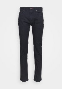 Jean slim bleu foncé avec poches avant, passants de ceinture et fermeture à bouton sur un fond clair uni.