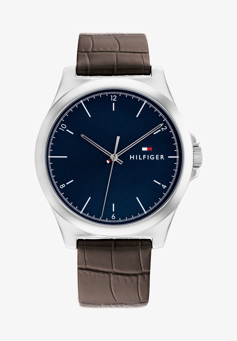 Tommy Hilfiger sat sa srebrnim kućištem od nehrđajućeg čelika, plavim brojčanikom, bijelim oznakama sati i smešnim kožnim remenom s uzorkom krokodila.