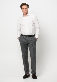 Camicia bianca con bottoni, pantaloni grigi su misura, cintura marrone scuro e mocassini marrone scuro. Design semplice con una vestibilità classica e tessuti lisci.