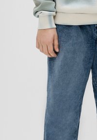 Lichtgrijze sweatshirt met geribde manchetten en een ronde hals, gecombineerd met donkerblauwe spijkerbroek met een licht vervaagde textuur.