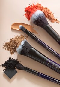Ensemble de quatre pinceaux de maquillage : poignées noires avec des accents violets. Comprend un pinceau à poudre, un pinceau à concealer, un pinceau de contour et un pinceau à ombre.