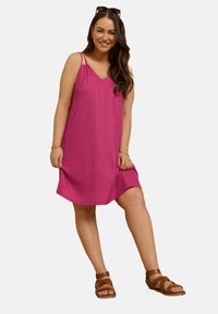 Rosa ärmlös klänning med vertikal ribbad textur, V-ringning och tunna remmar. Matchas med bruna sandaler med remmar.