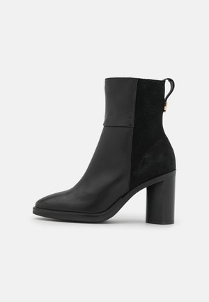 Bottine noire en cuir lisse et daim, dotée d'un talon carré et d'une languette à l'arrière. Design élégant avec un bout pointu.