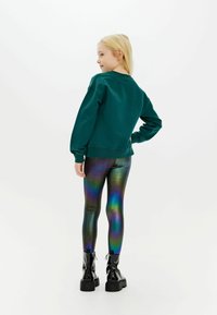 Grøn bomulds sweatshirt med lange ærmer, parret med iriserende leggings og sorte blanke ankelstøvler. Glatte teksturer, moderne pasform.