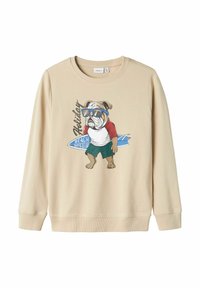 Sudadera beige con un bulldog ilustrado con gafas de sol, vistiendo una camiseta roja y blanca y pantalones cortos verdes; incluye el texto "Club de chicos de playa de vacaciones".