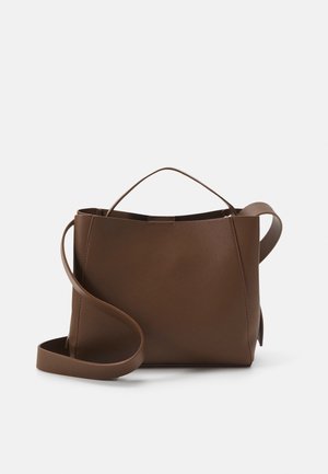 Sac à main en cuir marron avec une courte poignée supérieure et une longue bandoulière réglable sur un fond clair uni.