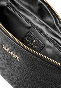 Borsetta in pelle nera con cerniera dorata parzialmente aperta che rivela l'interno in tessuto nero e una piccola etichetta in pelle con "LAZAROTTI" in lettere dorate.