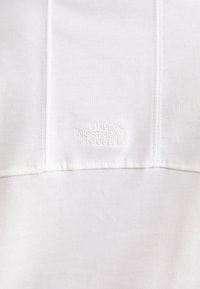 Hvid sweatshirt lavet af blødt bomuld med en tekstureret overflade. Har et præget logo, synlige sømme og et enkelt design.