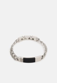 Bracelet en chaîne métallique argentée avec un accent rectangulaire noir texturé au centre, sécurisé par une fermeture à clip.