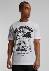 Hvid bomulds t-shirt med et sort grafisk print af en fodbold, skyer og sol med teksten "ALL-WEATHER SPORT" og "FOOTBALL'S COMING HOME."