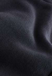 Tume sinine kangas, millel on sile ja pehme tekstuur, peene kudumismustriga ja kerge läikega. Erilisi mustreid ega aktsente ei ole näha.