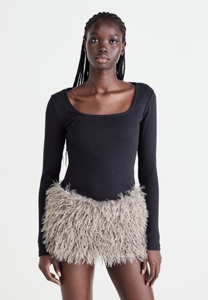 Langermet body i svart ribbestrikket stoff med en teksturert, fluffy, lys beige kant. Har firkantet utringning og tettsittende silhuett.
