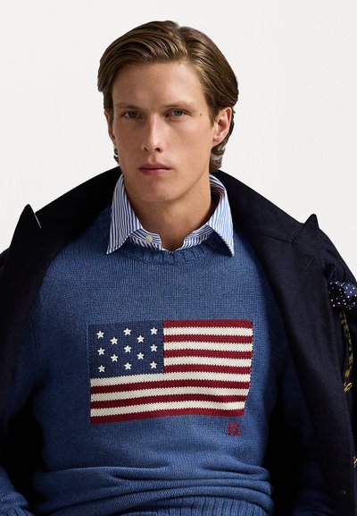 Blue knit sweater featuring an embroidered American flag. Includes a collared shirt underneath and a dark jacket, with RL logo detail.