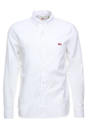 Chemise blanche à manches longues boutonnée avec col boutonné et petit logo rouge Levi's sur la poitrine gauche.
