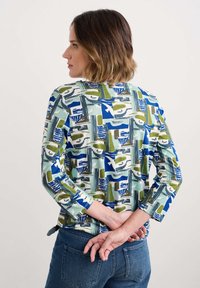 Camicia a maniche lunghe con un motivo geometrico in verde, blu e bianco. Realizzata in un tessuto morbido con una vestibilità comoda e scollo rotondo.