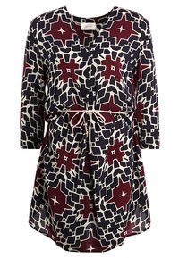 Šaty s potiskem, které mají hluboký výstřih do V, tříčtvrteční rukávy a stáhnutý pas s béžovým šňůrkovým páskem. Barvy zahrnují námořnickou modř, burgundskou a bílou.