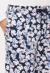 Pantalons à imprimé floral en navy, ornés de fleurs roses et bleues. Ceinture élastique avec cordon de serrage, poches latérales, fabriqués en tissu doux.
