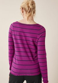 Lila gestreifter Pullover mit marineblauen horizontalen Linien, geripptem Halsausschnitt, langen Ärmeln und gewelltem Saum-Detail. Weicher Griff.
