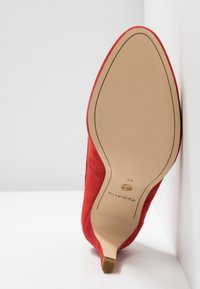 Chaussure à talon haut pointu en daim rouge, vue de la semelle avec semelle beige et petit talon aiguille, taille 37.