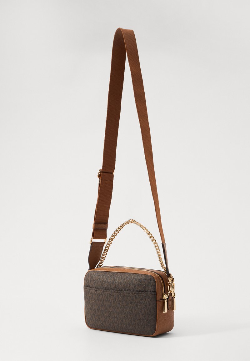 Borsa a tracolla marrone con design testurizzato, accentata da una catena dorata e cuffia regolabile. Presenta una chiusura con zip e motivo logo sul tessuto.