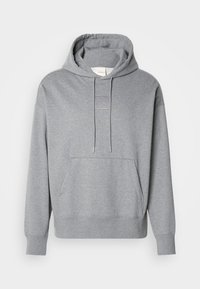 Sweat à capuche gris clair à enfiler avec cordons réglables, poche kangourou à l'avant, poignets côtelés et motif carré subtilement cousu sur la poitrine.
