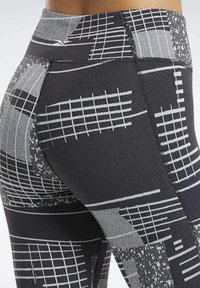 Czarne leggings sportowe z geometrycznym szarym wzorem, z liniami siatki i różnorodnymi teksturami. Wysoka talia i dopasowany krój.