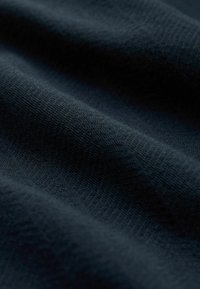 Tessuto blu scuro con una superficie morbida e testurizzata, caratterizzato da un sottile motivo a spina di pesce. Il materiale appare leggero e liscio.