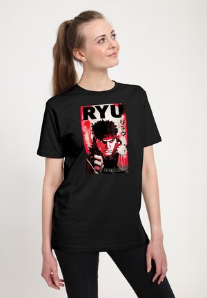 Ung kvinde med hestehale iført sort t-shirt med rød og sort Street Fighter-karakter Ryu med knyttet næve.
