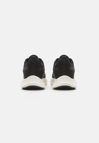 Schwarze Mesh-Sportschuhe mit einer weißen Sohle, ausgestattet mit einem strukturierten Obermaterial, flachen Schnürsenkeln und einer Zuglasche an der Ferse.