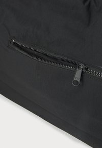 Black fabric bag featuring a visible zippered pocket with YKK hardware, smooth texture, and a simple rectangular design.