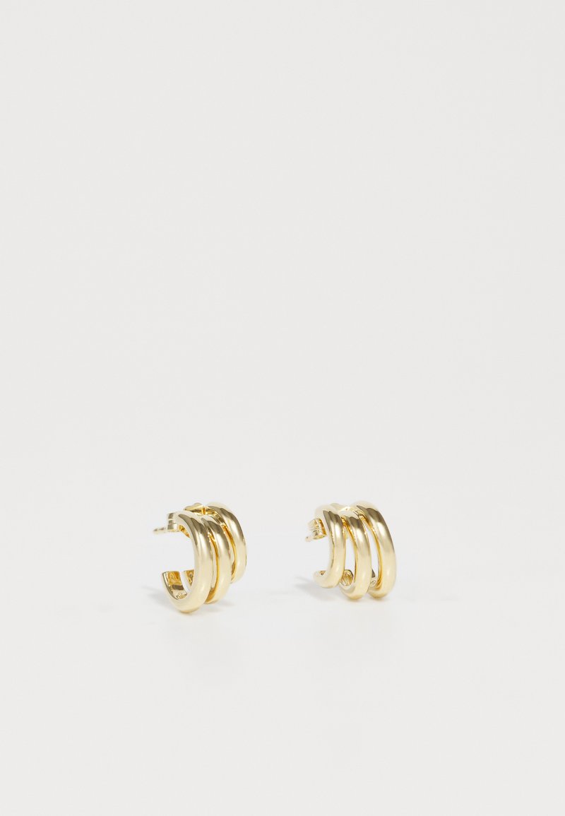 Zelta tonis auskari, kas veidoti ar trim savstarpēji savienotiem gredzeniem, ar gludu apdari un klipšu aizdari. Minimālisma un mūsdienīgu estētiku.