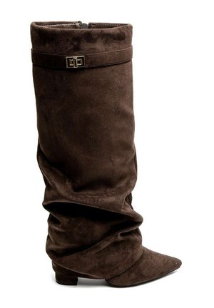 Botte haute en daim marron avec tige ample, bout pointu, petit talon et bride à boucle dorée décorative près du haut.